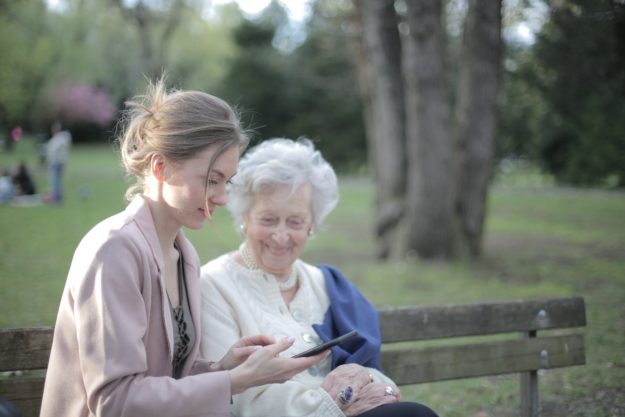 Life insurance claims - a young woman with an older woman sitting on a park bench.