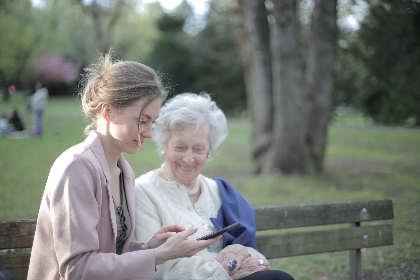 Life insurance claims - a young woman with an older woman sitting on a park bench.